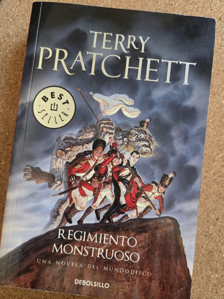 Portada de Regimiento Monstruoso en la que podemos ver a unos soldados (uno de ellos un gigantesco troll de piedra) subiendo una colina para plantar unas enaguas que hacen la función de bandera blanca en una escena que recuerda la mítica foto de Iwo Jima. Pero hay algo en esos soldados que no termina de encajar si te empiezas a fijar en los pequeños detalles...