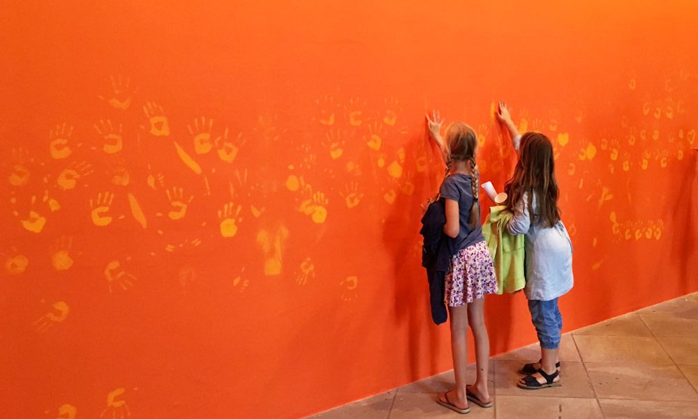 Enfants posent main sur l'oeuvre Orange