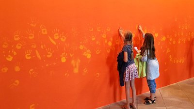 Enfants posent main sur l'oeuvre Orange