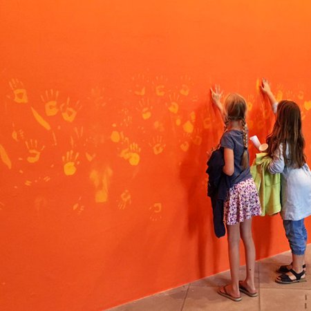 Enfants posent main sur l'oeuvre Orange