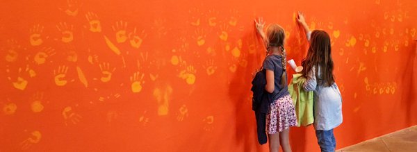 Enfants posent main sur l'oeuvre Orange