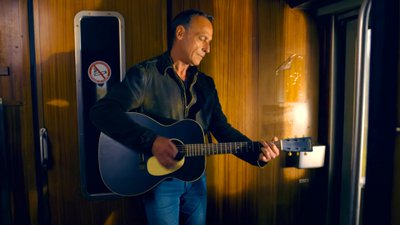 Luc Taff joue de la guitare dans le train