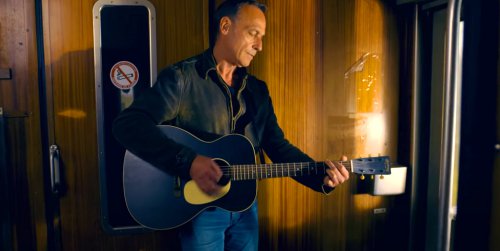 Luc Taff joue de la guitare dans le train