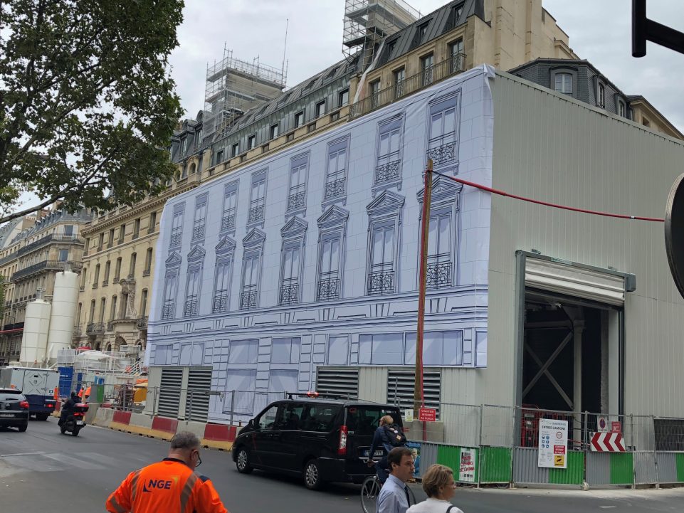Une façade d'immeuble recouverte d'une fresque en noir et blanc de fenêtres le temps des travaux