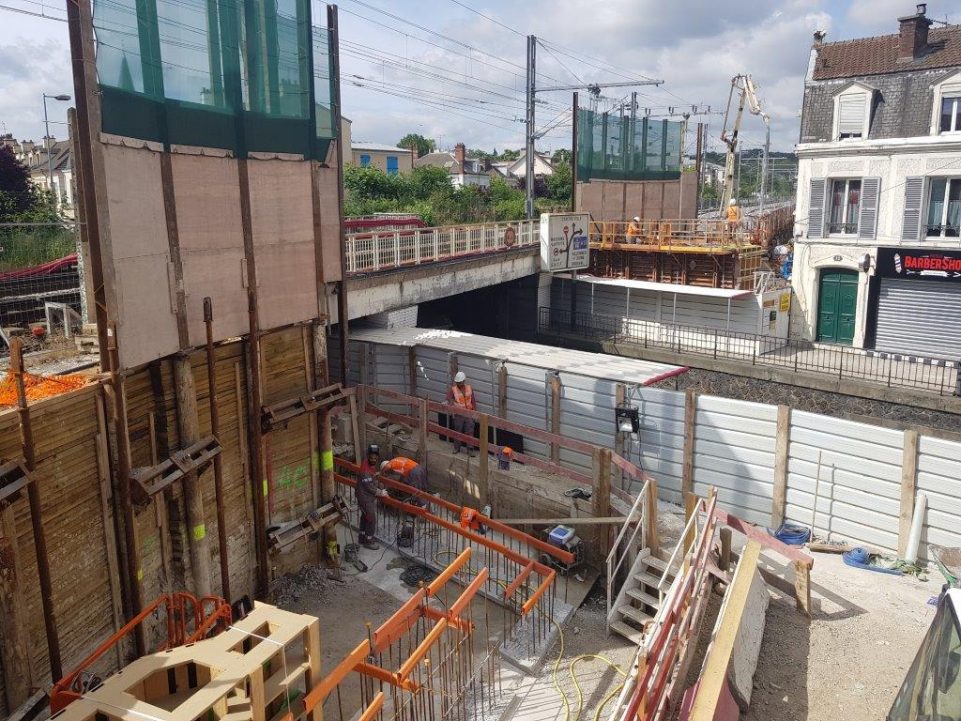 Image de chantier en plein jour sous un pont, des ouvriers sont à l'oeuvre