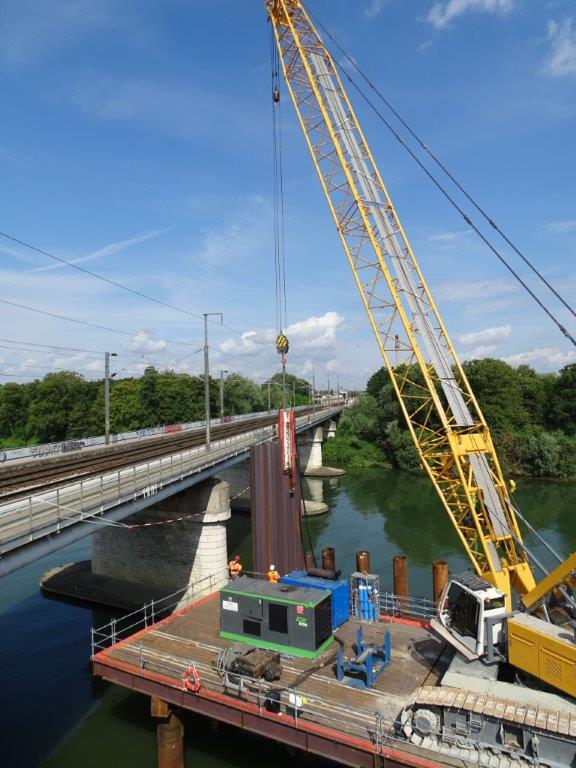 Une grue se déplace sur la Seine aux bords d'un pont pour la pose des palpanches